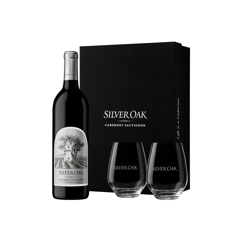 Silver Oak 2021 Alexander Valley Cabernet Sauvignon wine bottle with two stemless wine glasses glasses and a black gift box on a white background