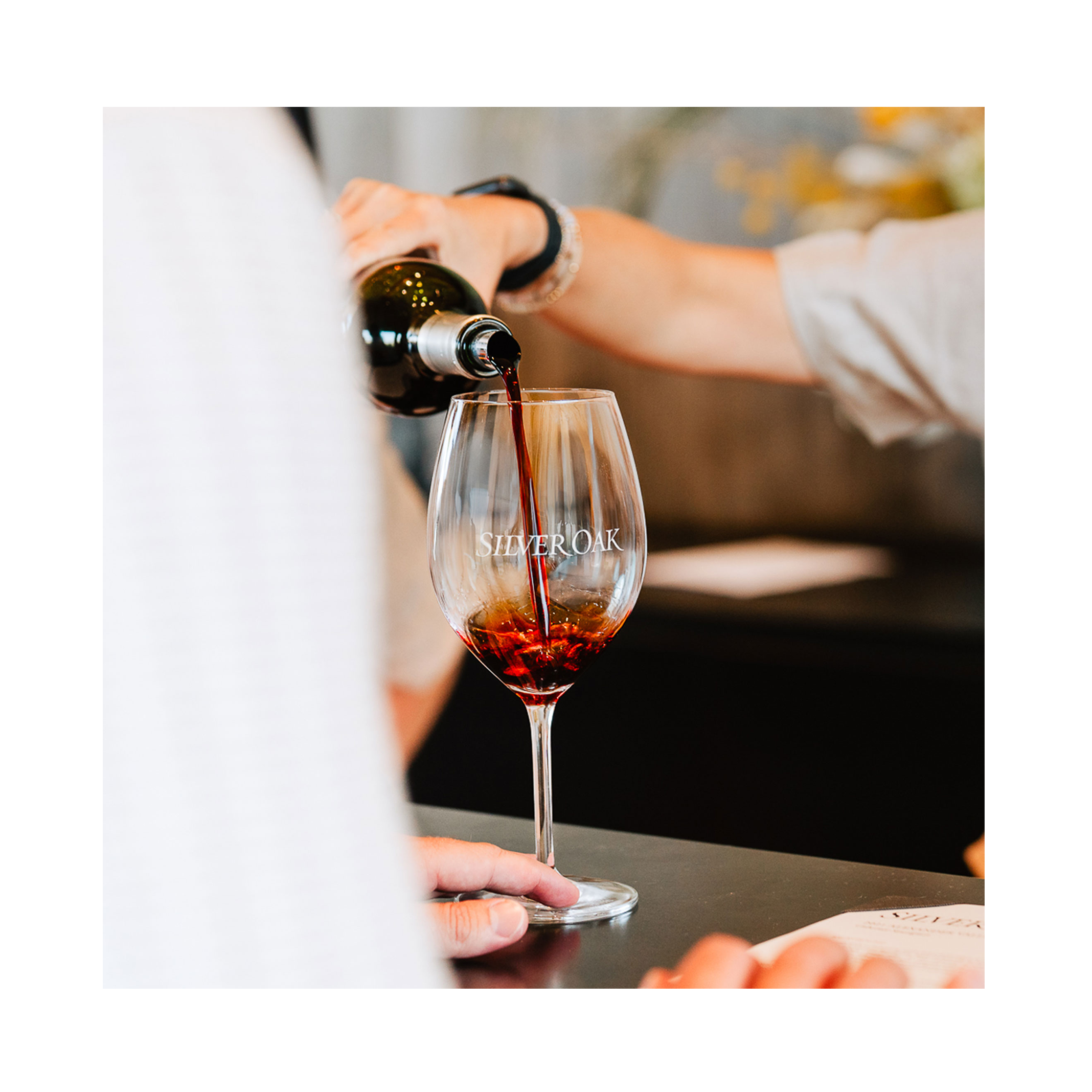 Person pouring red wine into a Silver Oak wine glass.
