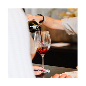 Person pouring red wine into a Silver Oak wine glass.